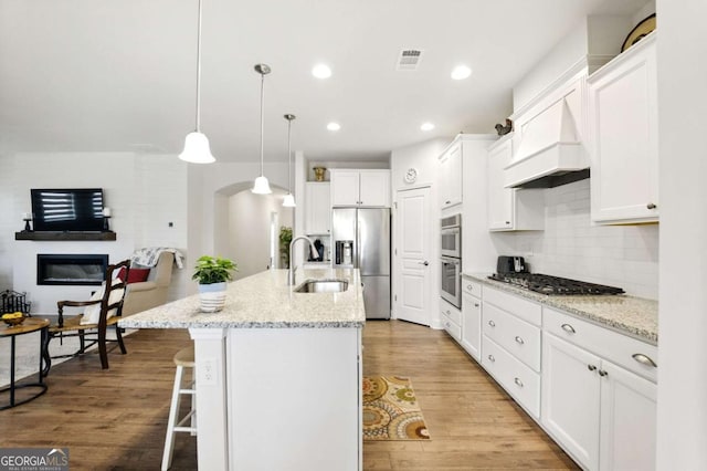 5744 Cypress Bluff Ln, Hoschton, GA 30548 - kitchen featuring appliances with stainless steel finishes, premium range hood, a kitchen breakfast bar, white cabinetry, and decorative backsplash
