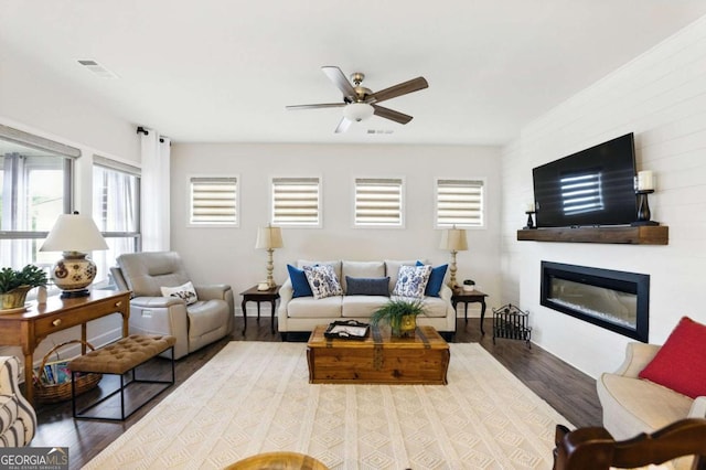 5744 Cypress Bluff Ln, Hoschton, GA 30548 - living room featuring wood finished floors, a glass covered fireplace, and a ceiling fan