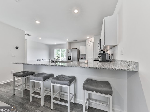 520 Pemberton St, Euharlee, GA 30145 - kitchen with stainless steel fridge, light stone counters, a peninsula, white cabinets, and dark wood-style floors