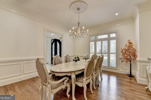 8230 Royal Melbourne Way, Duluth, GA 30097 - dining area with a chandelier, a decorative wall, light wood-style floors, wainscoting, and ornamental molding