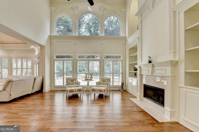 8230 Royal Melbourne Way, Duluth, GA 30097 - living room featuring a high ceiling, built in features, plenty of natural light, a high end fireplace, and light wood-style floors