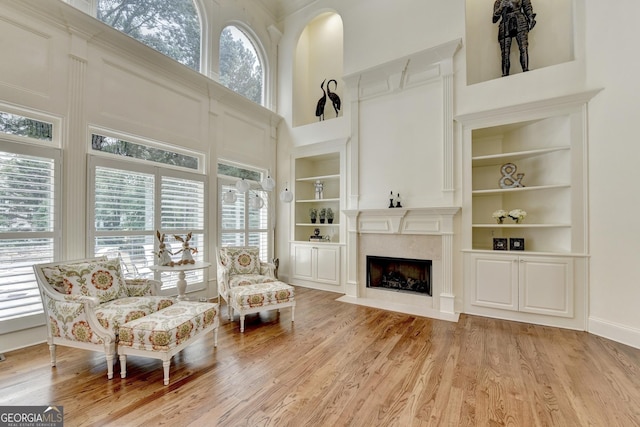8230 Royal Melbourne Way, Duluth, GA 30097 - living area featuring built in shelves, a towering ceiling, a premium fireplace, and light wood finished floors