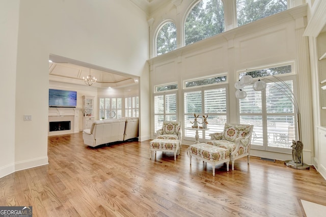 8230 Royal Melbourne Way, Duluth, GA 30097 - living room featuring ornamental molding, a towering ceiling, a fireplace, light wood-style flooring, and a chandelier