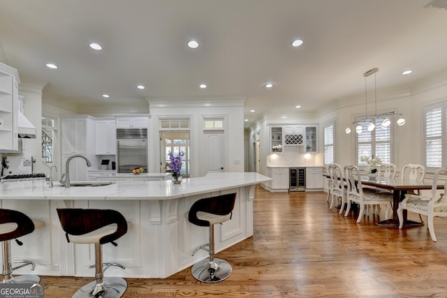 8230 Royal Melbourne Way, Duluth, GA 30097 - kitchen with appliances with stainless steel finishes, beverage cooler, ornamental molding, white cabinets, and a breakfast bar