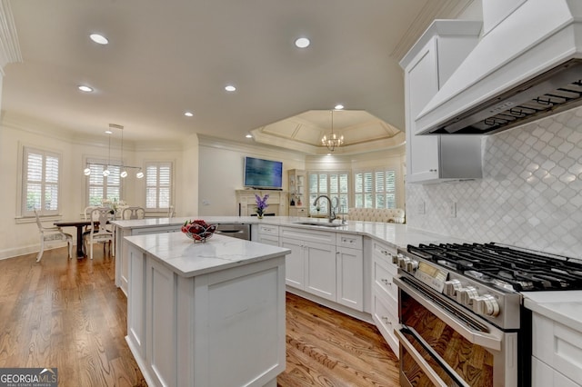 8230 Royal Melbourne Way, Duluth, GA 30097 - kitchen with range hood, stainless steel appliances, crown molding, a chandelier, and a peninsula