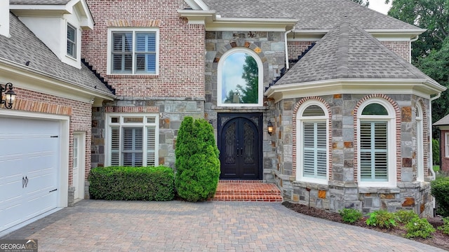 8230 Royal Melbourne Way, Duluth, GA 30097 - view of exterior entry with french doors, stone siding, a shingled roof, and decorative driveway