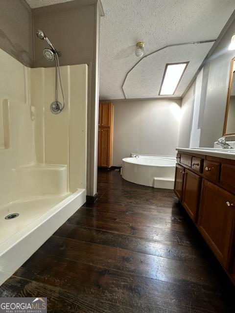3171 Wagnon Mill Rd, Bishop, GA 30621 - full bathroom with a shower stall, a garden tub, vanity, wood-type flooring, and a textured ceiling