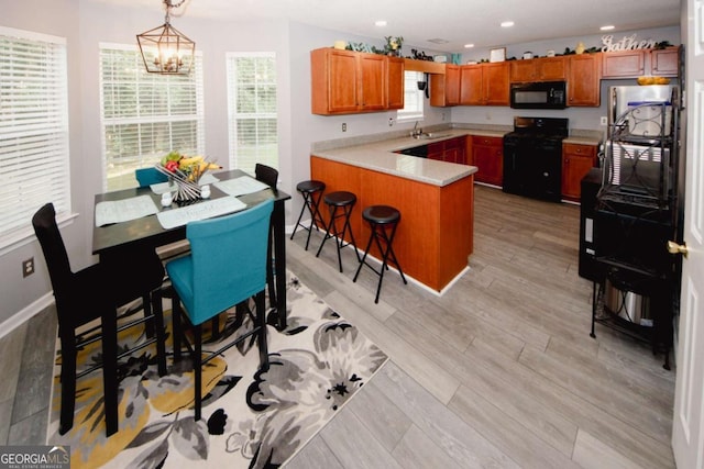 1964 Cutters Mill Way, Lithonia, GA 30058 - kitchen with black appliances, a peninsula, light countertops, a chandelier, and brown cabinets
