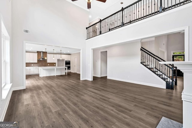 7449 Waterview Cv, Douglasville, GA 30135 - unfurnished living room featuring a high ceiling, ceiling fan, stairway, and dark wood-style floors