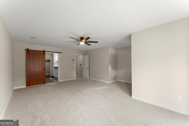 1655 Oak Crest Ct, Marietta, GA 30066 - unfurnished bedroom featuring a barn door, light colored carpet, and a ceiling fan