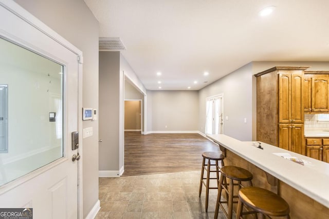 132 Hidden Creek Cir, Lizella, GA 31052 - kitchen featuring a breakfast bar, recessed lighting, light countertops, brown cabinets, and open floor plan