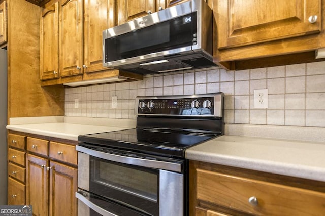 132 Hidden Creek Cir, Lizella, GA 31052 - kitchen with appliances with stainless steel finishes, brown cabinets, light countertops, and backsplash
