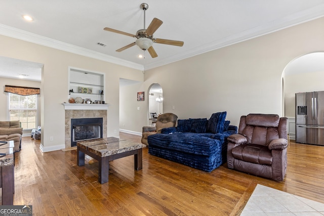 408 Dixieland Dr, Byron, GA 31008 - living room featuring arched walkways, wood finished floors, a ceiling fan, a tiled fireplace, and ornamental molding
