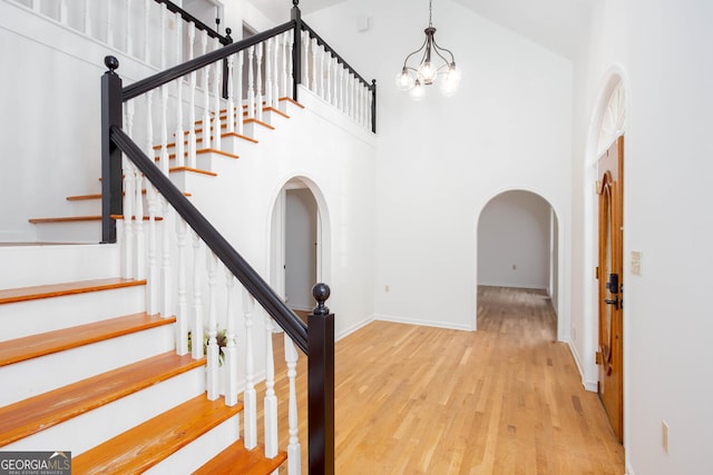 5491 Hiram Rd, Powder Springs, GA 30127 - staircase featuring wood finished floors, arched walkways, a high ceiling, and a chandelier