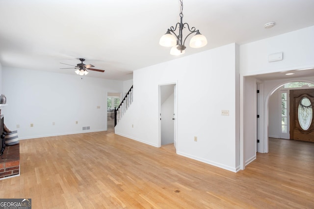 5491 Hiram Rd, Powder Springs, GA 30127 - unfurnished living room featuring stairway, ceiling fan, light wood finished floors, arched walkways, and a chandelier