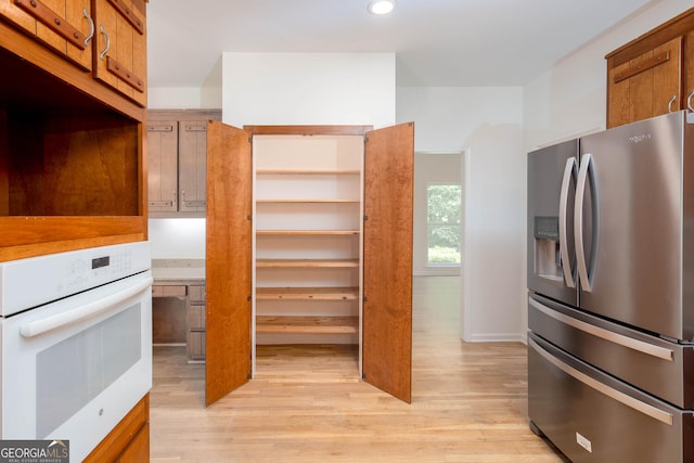 5491 Hiram Rd, Powder Springs, GA 30127 - kitchen with stainless steel refrigerator with ice dispenser, oven, light wood finished floors, brown cabinets, and recessed lighting