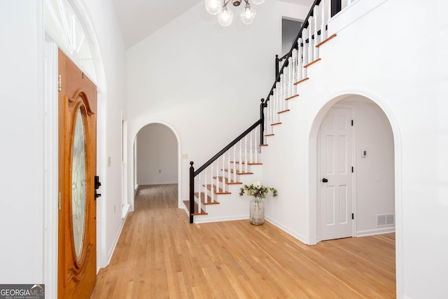 5491 Hiram Rd, Powder Springs, GA 30127 - foyer featuring arched walkways, light wood-style floors, stairs, a towering ceiling, and a chandelier