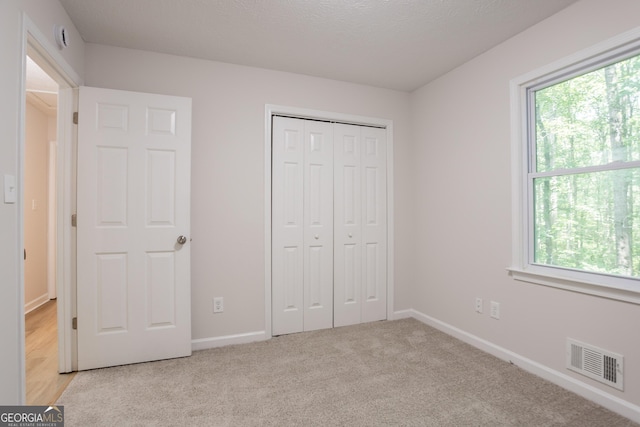356 Waterway Trl, Powder Springs, GA 30127 - unfurnished bedroom featuring multiple windows, light colored carpet, a closet, and a textured ceiling
