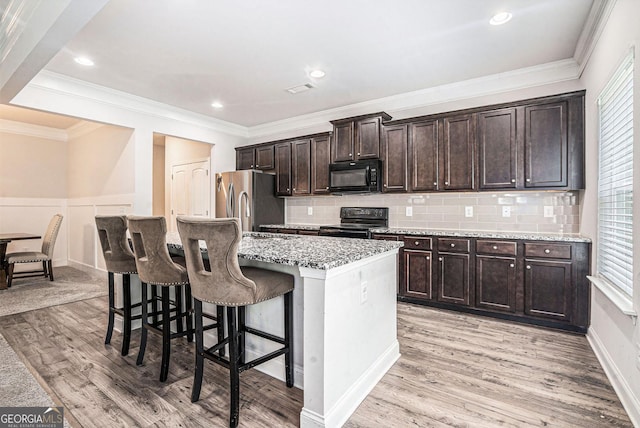 154 Laurel Cove Dr, Hoschton, GA 30548 - kitchen featuring black appliances, a kitchen bar, dark brown cabinets, a kitchen island with sink, and tasteful backsplash