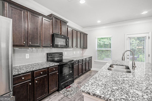 154 Laurel Cove Dr, Hoschton, GA 30548 - kitchen with black appliances, light wood-style floors, ornamental molding, backsplash, and light stone counters