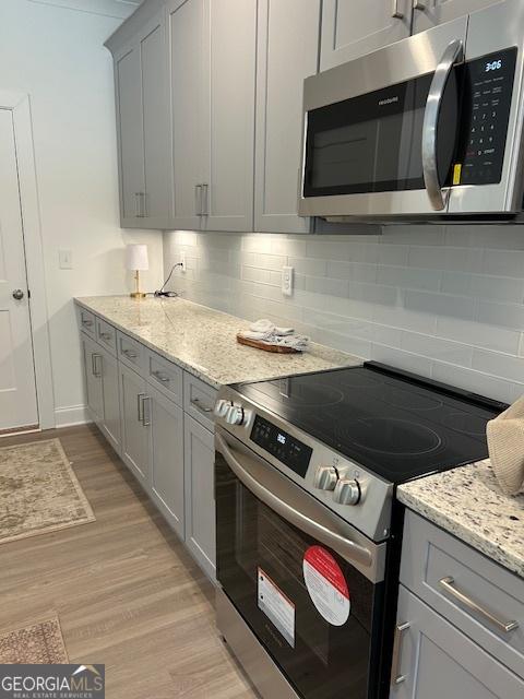 322 Heron St, Ball Ground, GA 30107 - kitchen with stainless steel appliances, gray cabinets, light wood finished floors, and backsplash