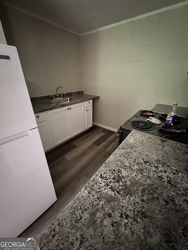 1040 Chestney St, Macon, GA 31217 - kitchen featuring electric range, dark wood-style floors, white cabinets, crown molding, and freestanding refrigerator