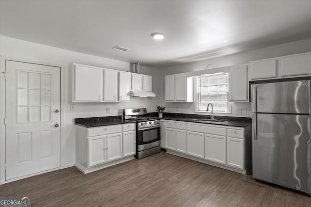 5861 Community Rd SE, Mableton, GA 30126 - kitchen with appliances with stainless steel finishes, under cabinet range hood, dark countertops, and white cabinets