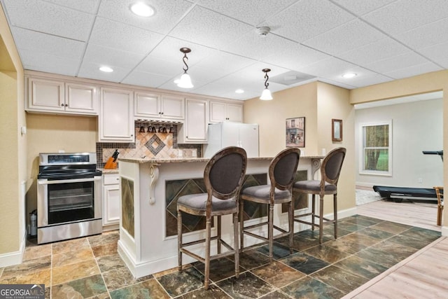 2118 Chatham, Dalton, GA 30720 - kitchen with stainless steel electric stove, decorative backsplash, freestanding refrigerator, a kitchen bar, and a drop ceiling