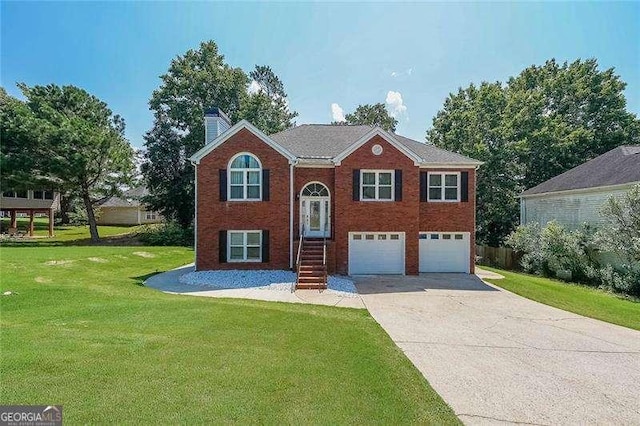 503 Rising Dr, Woodstock, GA 30189 - bi-level home featuring an attached garage, concrete driveway, a front lawn, a chimney, and brick siding