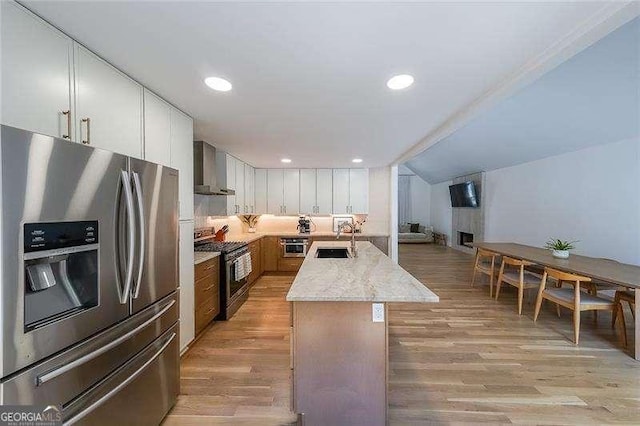 503 Rising Dr, Woodstock, GA 30189 - kitchen with appliances with stainless steel finishes, wall chimney range hood, light wood-style flooring, white cabinetry, and recessed lighting