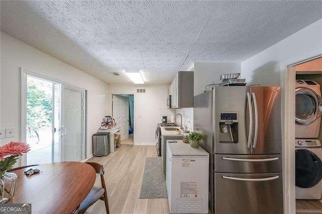 503 Rising Dr, Woodstock, GA 30189 - kitchen with stainless steel fridge, stacked washer / dryer, light wood-type flooring, a textured ceiling, and light countertops