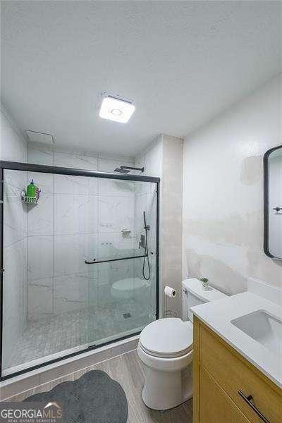 503 Rising Dr, Woodstock, GA 30189 - bathroom featuring vanity, a stall shower, and wood finished floors