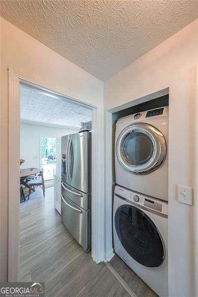 503 Rising Dr, Woodstock, GA 30189 - washroom with stacked washing machine and dryer, wood finished floors, and a textured ceiling