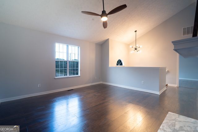 2333 Wilkins Cv, Decatur, GA 30035 - empty room with ceiling fan, dark wood-style flooring, a chandelier, and high vaulted ceiling
