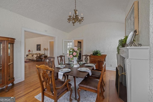 204 S Jefferson Ave, Eatonton, GA 31024 - dining room featuring a textured wall, lofted ceiling, wood finished floors, a chandelier, and a textured ceiling