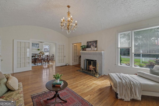 204 S Jefferson Ave, Eatonton, GA 31024 - living area with wood finished floors, a chandelier, vaulted ceiling, a textured ceiling, and a fireplace