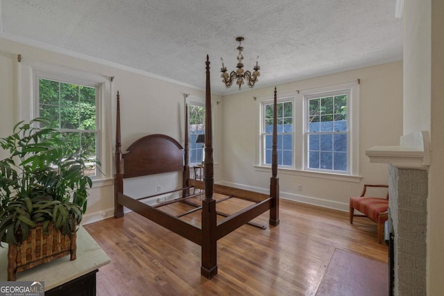 204 S Jefferson Ave, Eatonton, GA 31024 - bedroom with a chandelier, wood finished floors, a textured ceiling, and crown molding