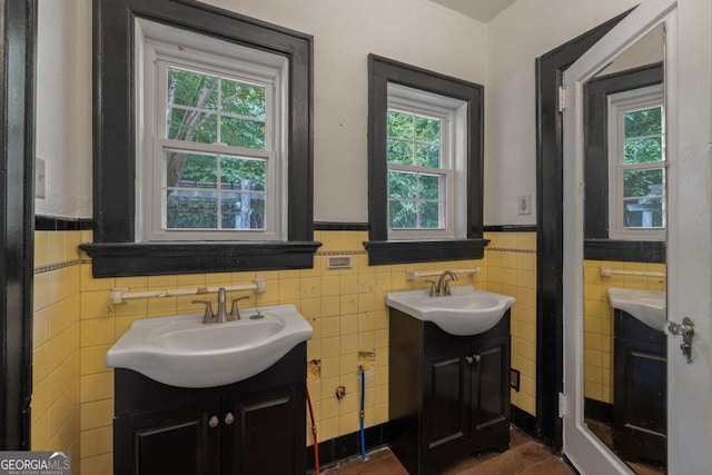 204 S Jefferson Ave, Eatonton, GA 31024 - bathroom featuring two vanities, tile walls, a wainscoted wall, and wood finished floors
