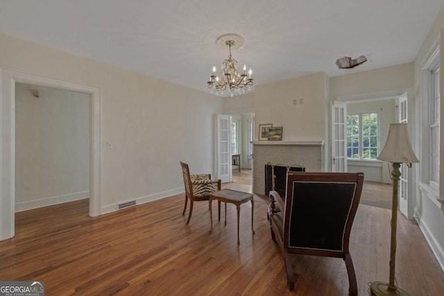 204 S Jefferson Ave, Eatonton, GA 31024 - dining area featuring wood finished floors, a chandelier, and a brick fireplace