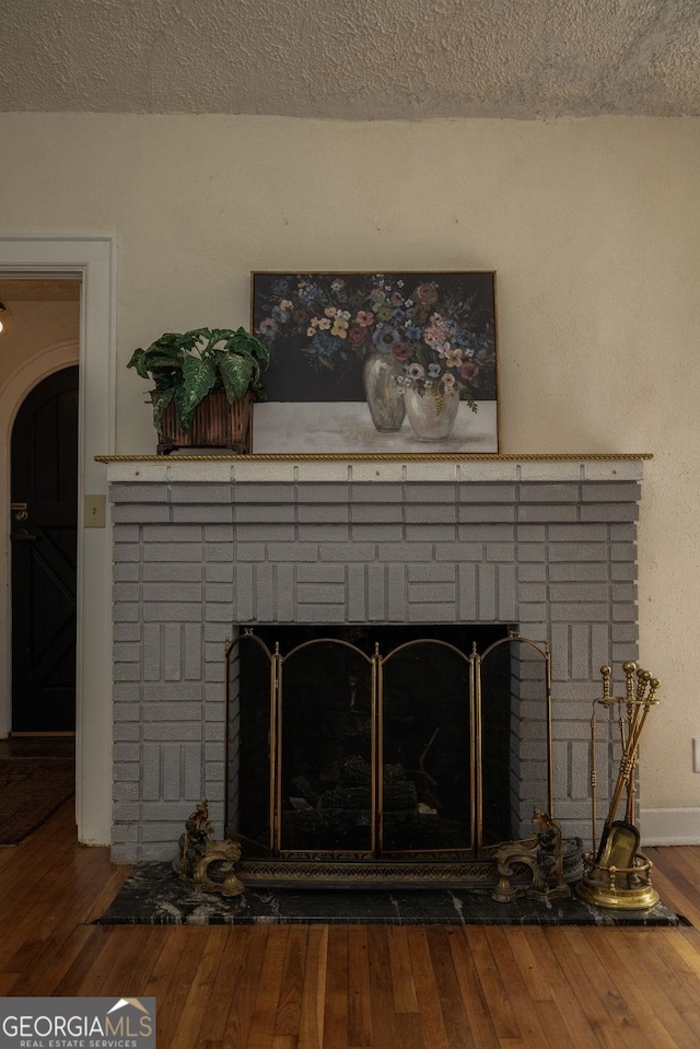 204 S Jefferson Ave, Eatonton, GA 31024 - detailed view of a fireplace, a textured ceiling, wood finished floors, and arched walkways