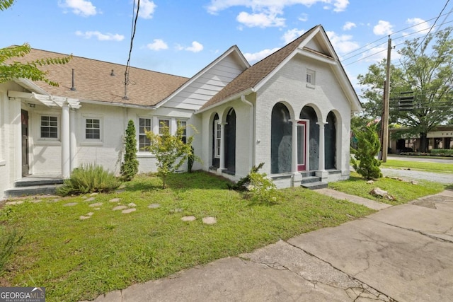 204 S Jefferson Ave, Eatonton, GA 31024 - view of front of home with a shingled roof, a front lawn, and brick siding
