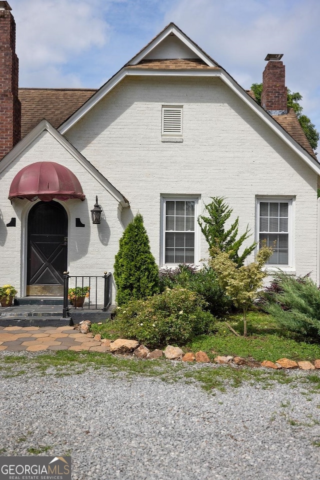 204 S Jefferson Ave, Eatonton, GA 31024 - view of front of property featuring a chimney, brick siding, and roof with shingles