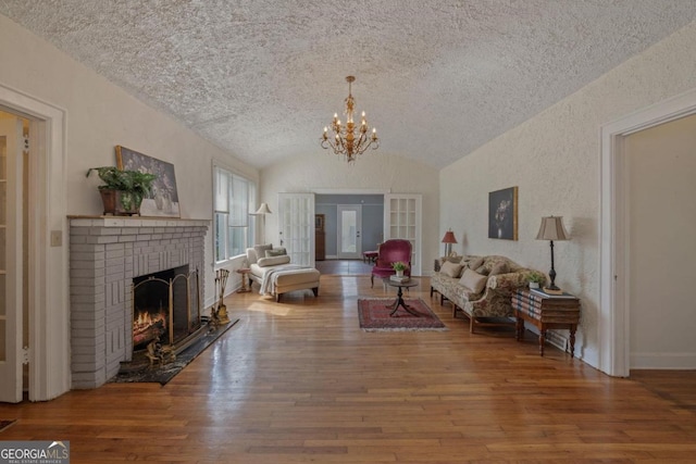 204 S Jefferson Ave, Eatonton, GA 31024 - living area with vaulted ceiling, a textured ceiling, wood-type flooring, a fireplace, and a chandelier