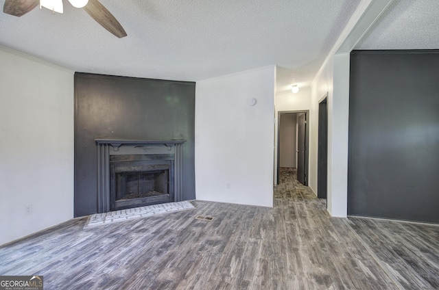 1525 Bailey Rd, Aragon, GA 30104 - unfurnished living room with wood finished floors, ceiling fan, a textured ceiling, a fireplace with flush hearth, and ornamental molding