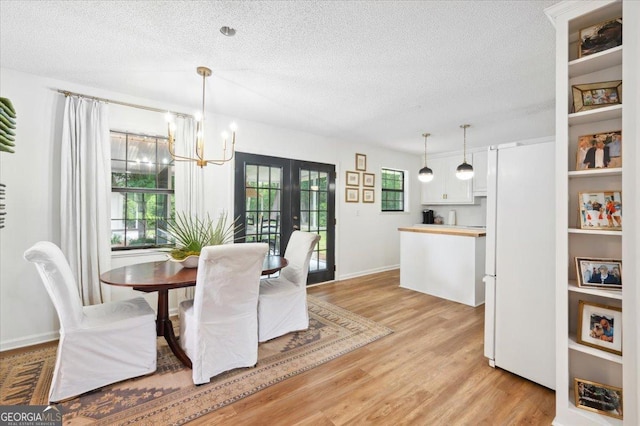 711 Chapman St, Blackshear, GA 31516 - dining space featuring a textured ceiling, a chandelier, light wood-type flooring, and french doors