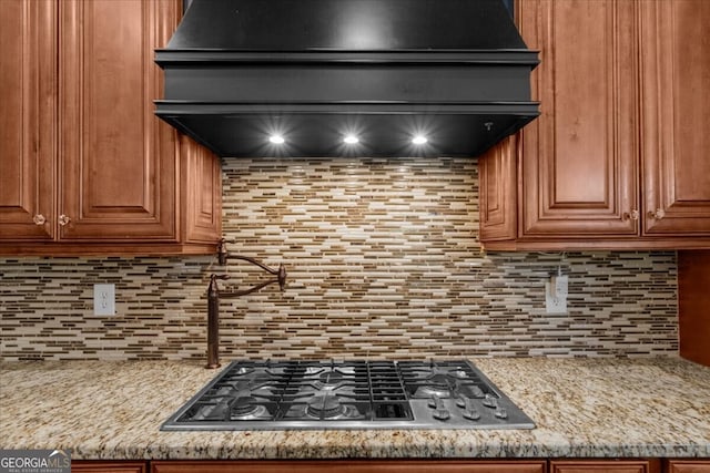 932 Shadowford Fls, Lithonia, GA 30058 - kitchen featuring exhaust hood, stainless steel gas stovetop, decorative backsplash, and brown cabinets