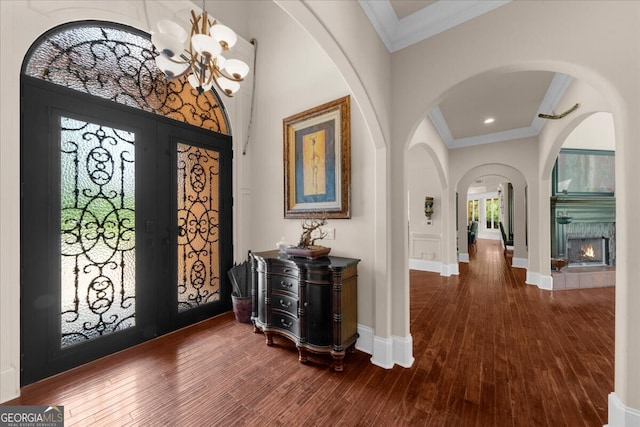932 Shadowford Fls, Lithonia, GA 30058 - entrance foyer featuring crown molding, a chandelier, dark wood-style flooring, arched walkways, and a warm lit fireplace