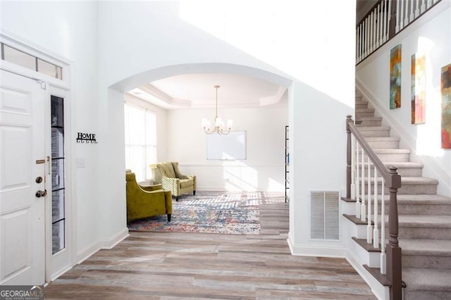 2516 Woolwich Ct, Acworth, GA 30101 - entrance foyer with wood finished floors, arched walkways, stairway, a chandelier, and a raised ceiling