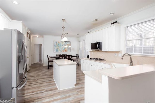 2516 Woolwich Ct, Acworth, GA 30101 - kitchen with stainless steel appliances, light wood finished floors, a kitchen island, light countertops, and ornamental molding