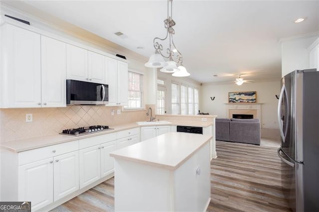 2516 Woolwich Ct, Acworth, GA 30101 - kitchen featuring appliances with stainless steel finishes, light countertops, a center island, white cabinetry, and light wood-style floors